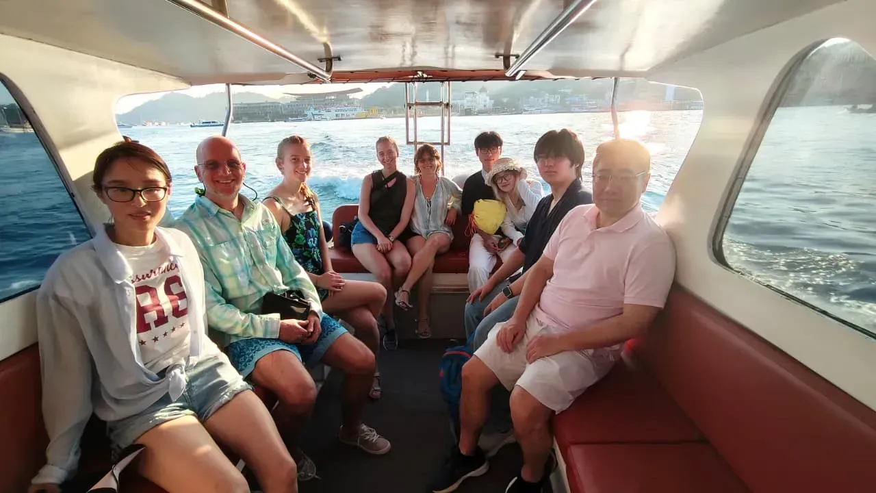 Guests relaxing in boat cabin at sunset departure, Komodo tour